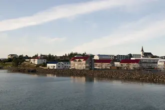 View of Borgarnes, a historic seaside village in Iceland, showcasing colorful houses with red rooftops, a charming church, and serene coastal waters under soft evening light. Ideal stop on Icelandic self-drive tours.