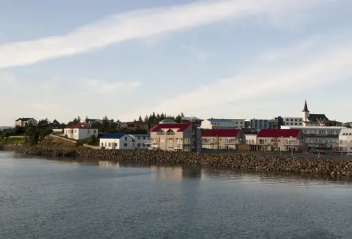 View of Borgarnes, a historic seaside village in Iceland, showcasing colorful houses with red rooftops, a charming church, and serene coastal waters under soft evening light. Ideal stop on Icelandic self-drive tours.