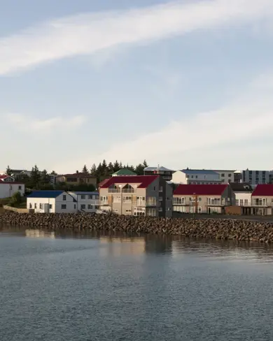View of Borgarnes, a historic seaside village in Iceland, showcasing colorful houses with red rooftops, a charming church, and serene coastal waters under soft evening light. Ideal stop on Icelandic self-drive tours.
