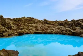Blue Lagoon surrounded by moss covered lava under a blue sky located close to Keflavik Airport Iceland.