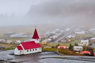 Vik i Myrdal Church with red roof standing above the town.