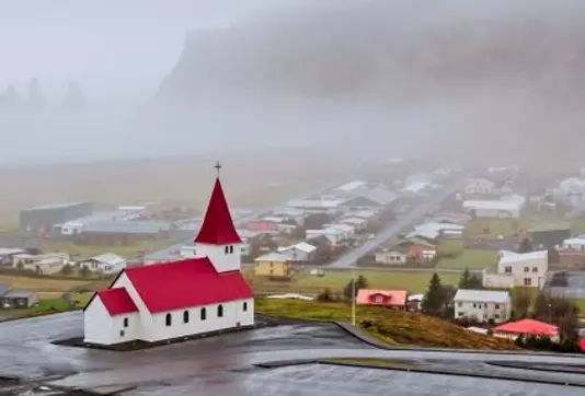 Vik i Myrdal Church with red roof standing above the town.
