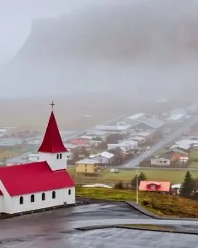 Vik i Myrdal Church with red roof standing above the town.