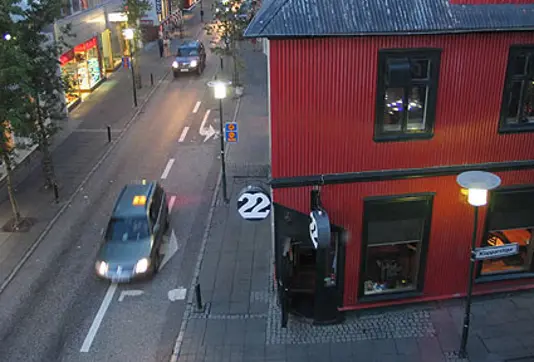 A street view of 22 Bar in downtown Reykjavík, showcasing its iconic red building and bustling street corner at dusk.