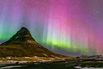 Colorful Aurora Borealis in Pink, Purple, Green, and Blue Over Kirkjufell Mountain in Iceland.