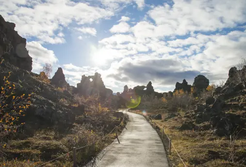 Pathway through lava formations in Dimmuborgir, Mývatn, Iceland, under a bright sky, part of a scenic tour around Iceland with Travel Reykjavik.