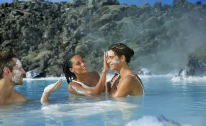 Guests applying silica mud face masks at the Blue Lagoon geothermal spa, surrounded by volcanic rocks and steam in Iceland