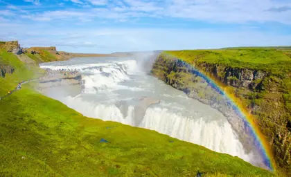 Breathtaking view of Gullfoss Waterfall, showcasing the cascading waters and vibrant rainbow, an essential stop on the Journey Around Iceland tour.