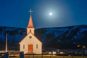 Dark Night over Vikurkirkja Church in winter under a full moon.