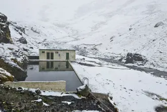 Snowing at Seljavallalaug Hot Spring Swimming Pool and Old Concrete Hut in Iceland in Winter.